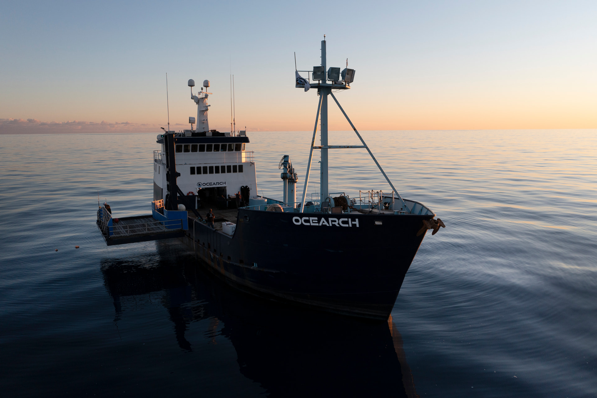 The OCEARCH research vessel at sunrise on a calm sea