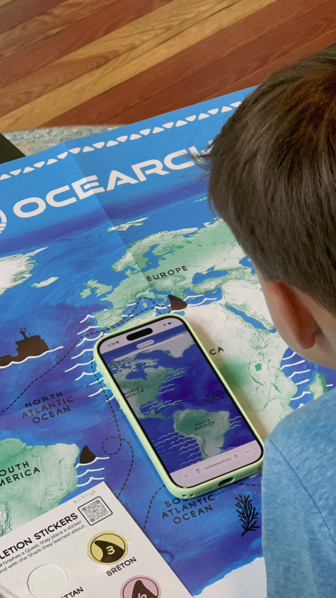 An Explorer following a shark Quest on a phone over the printed tracking map