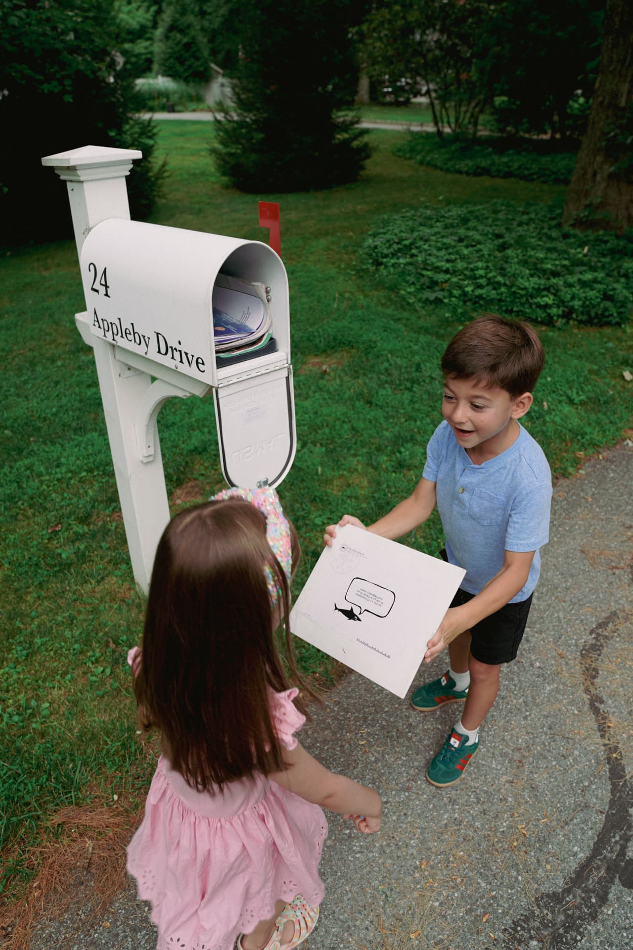 Two children excitedly pulling their OCEARCH Adventure kit from the mailbox