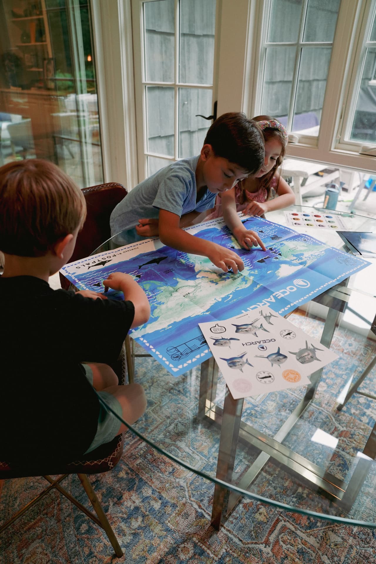 Three kids gathered around a table exploring the OCEARCH shark tracking map together