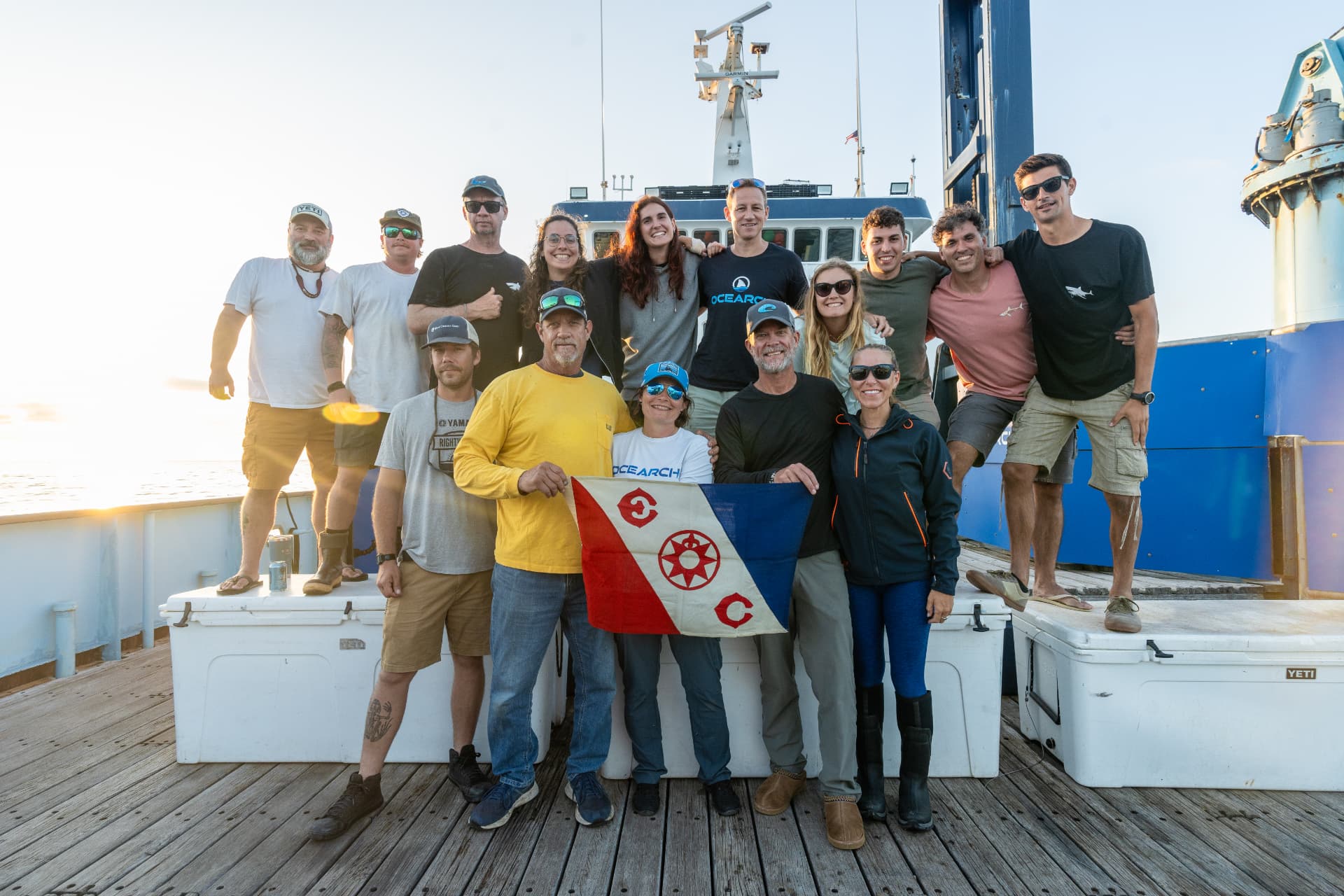 The OCEARCH crew standing together on the deck of the research vessel in early morning light